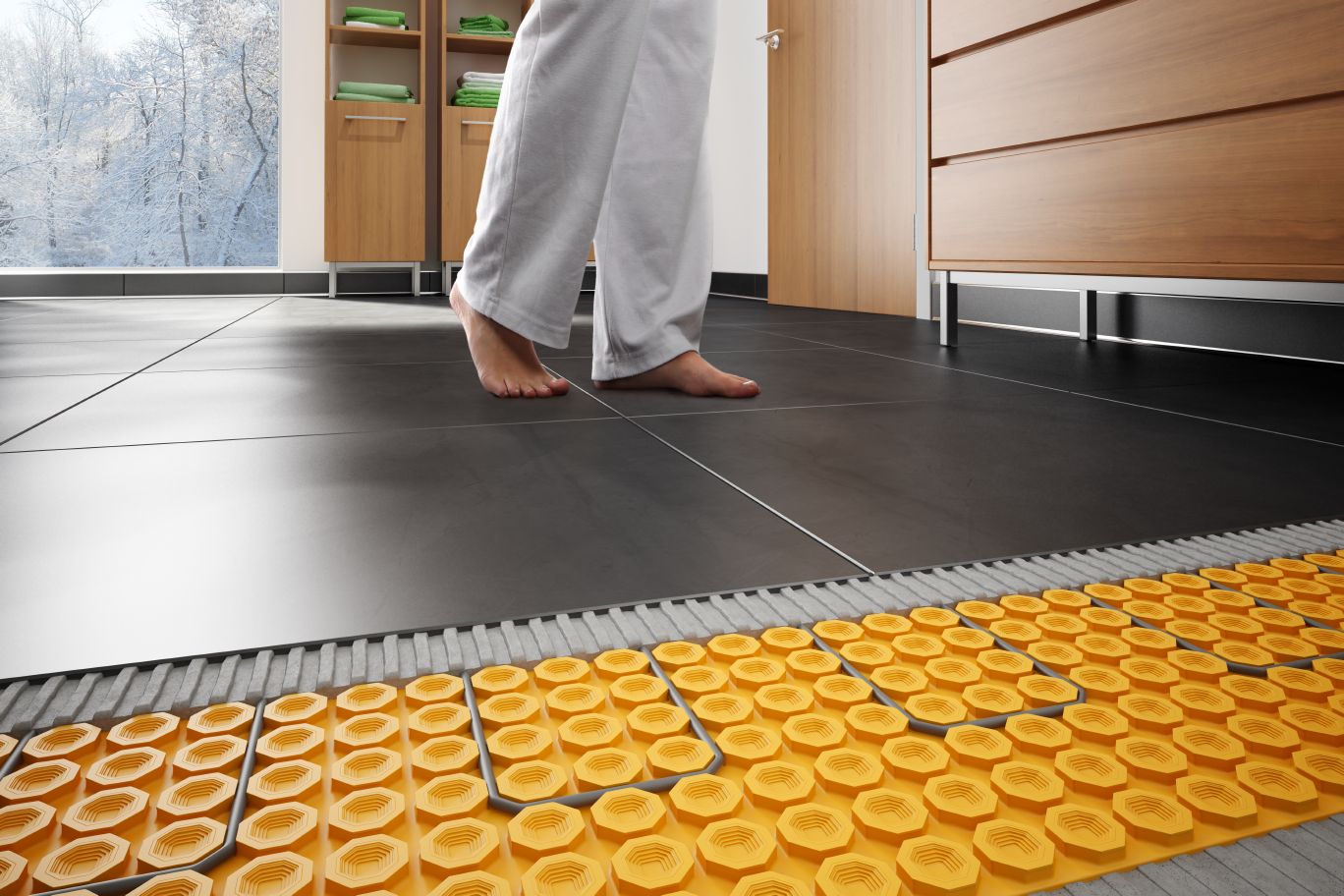 Picture from Schluter showing feet on a floor that is heated with Ditra in floor heating